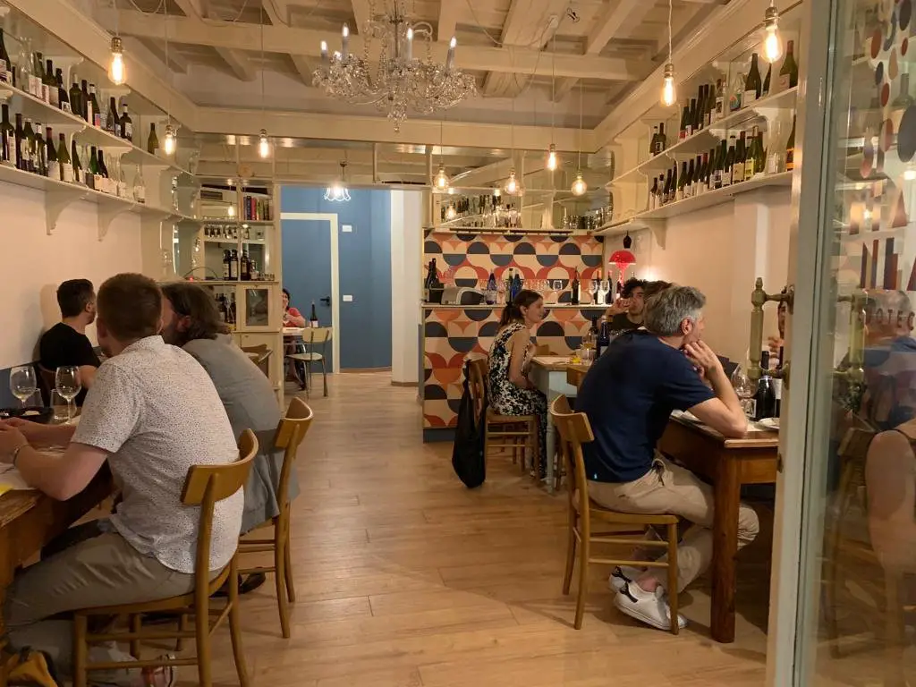 Enoteca Spontanea interior of a wine bar with people sitting and tasting wine